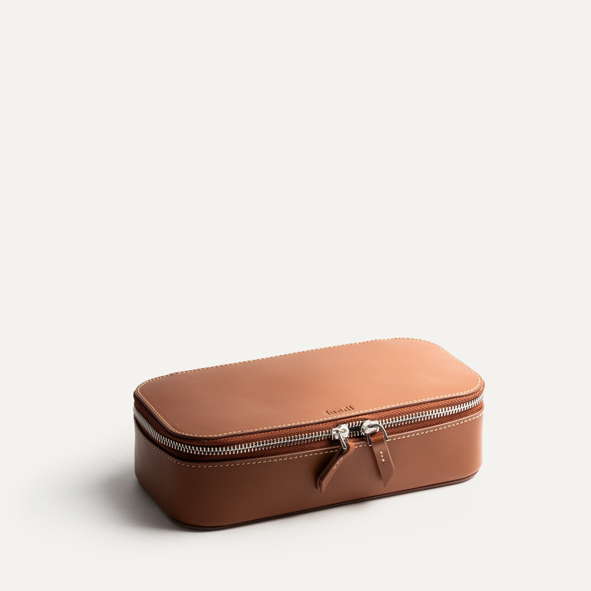 Trousse de toilette de luxe femme fermée en cuir cognac robuste et élégante.