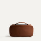 Trousse de toilette homme en cuir cognac avec une poignée arrière intégrée.