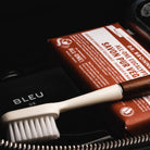 Gros plan sur le contenu d'une trousse de toilette de luxe femme incluant savon, parfum et brosse.