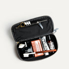 Trousse de toilette homme luxe remplie de produits de soin, vue intérieure avec accessoires rangés.