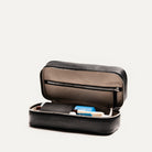 Trousse de toilette de luxe ouverte en cuir noir, avec rangements intérieurs élégants et zippés pour les produits de soin.