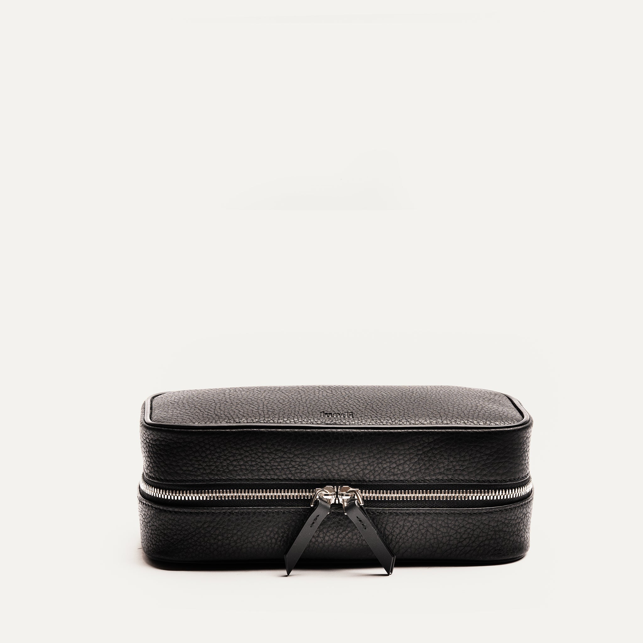 Trousse de toilette homme luxe fermée, en cuir pleine fleur noir avec détails soignés et doubles tirettes en cuir.