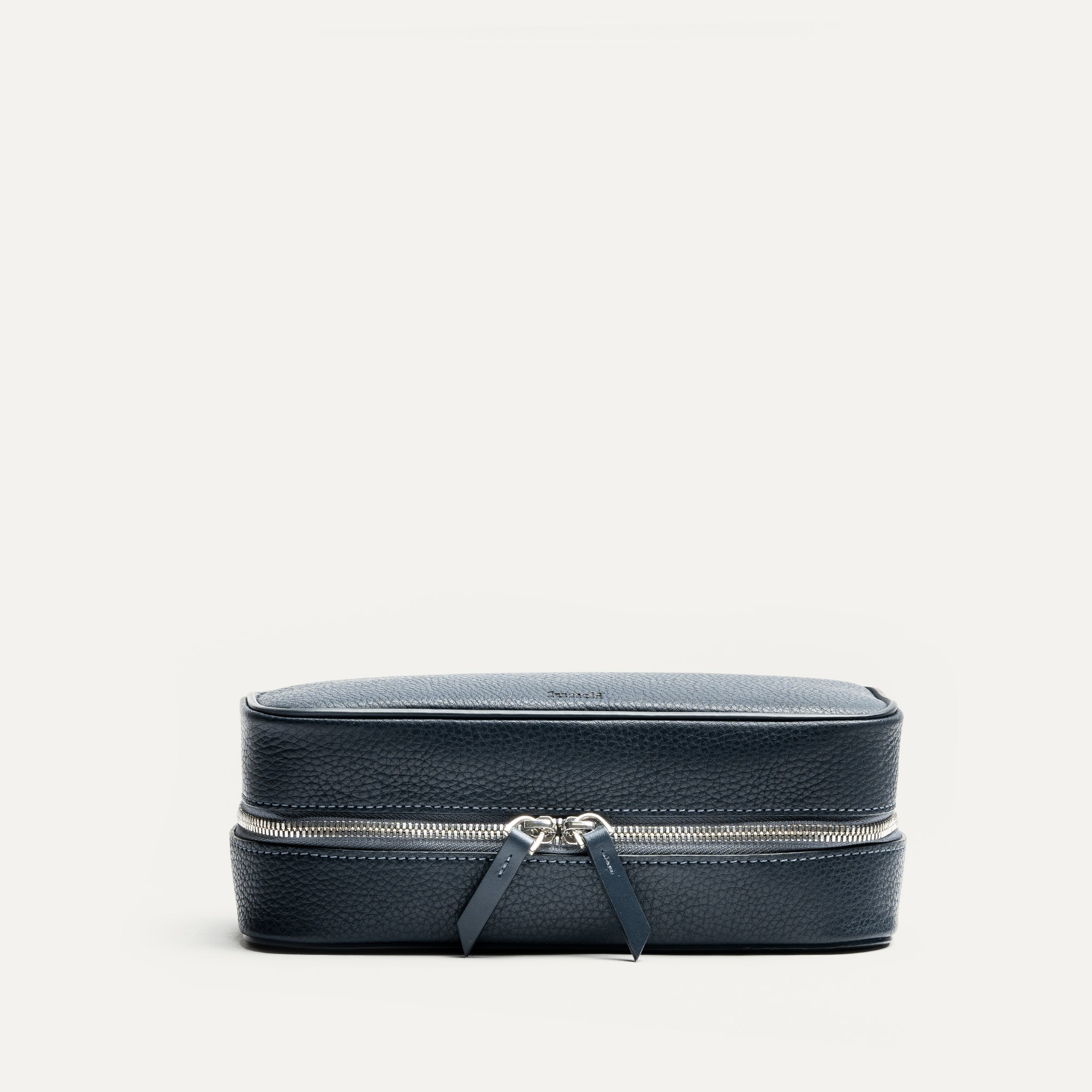 Grande trousse de toilette pour homme fermée, en cuir bleu marine, dotée d’une double fermeture éclair robuste.
