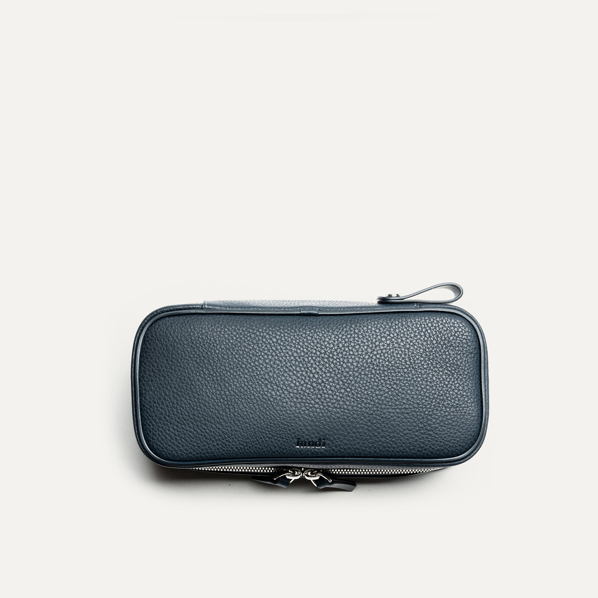 Trousse de toilette femme vue de dessus, en cuir texturé bleu marine, élégante et pratique pour les voyages.