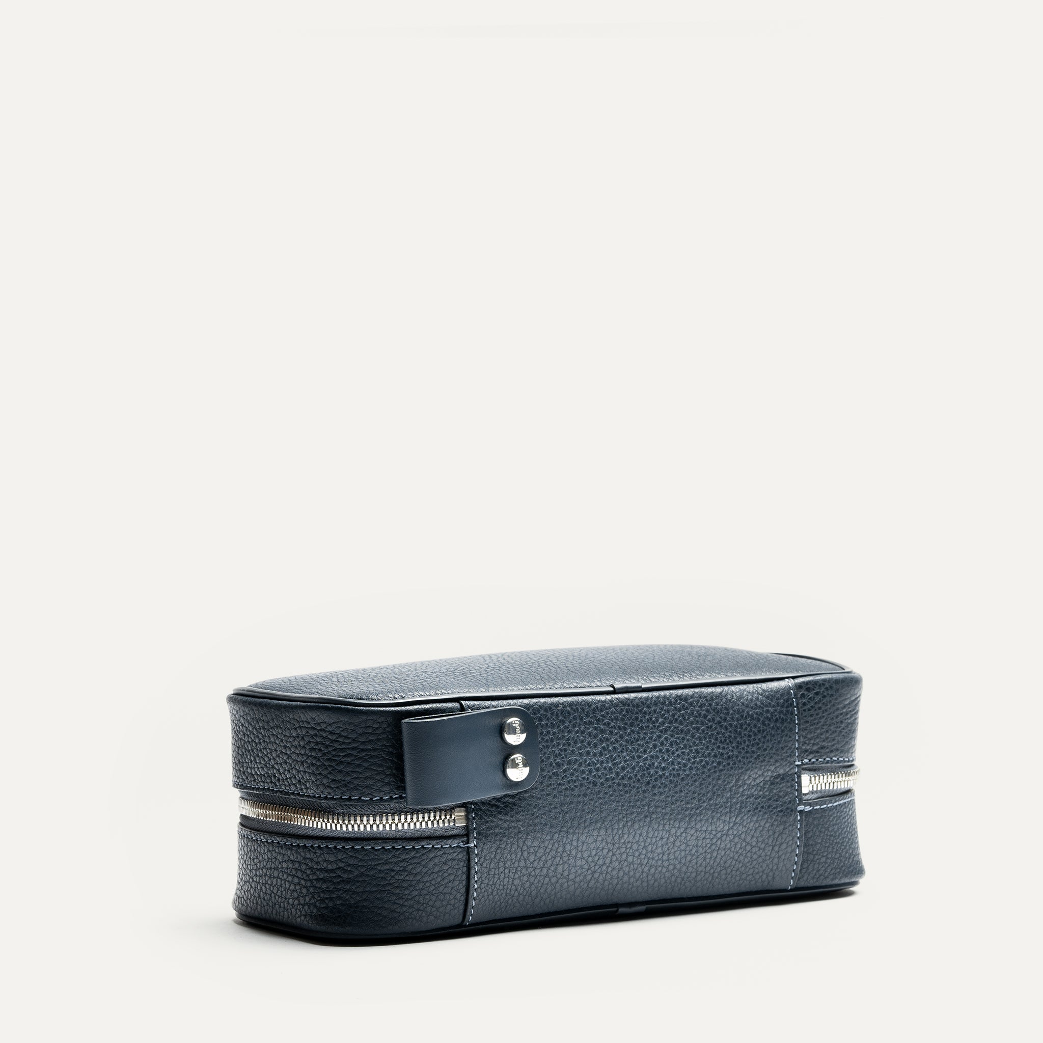 Trousse de toilette homme luxe vue de l’arrière, avec poignée latérale et finition en cuir pleine fleur bleu marine.
