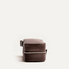 Trousse de toilette femme grand format vue de côté, en cuir marron grainé avec fermeture éclair solide.