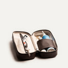 Trousse de toilette de luxe femme ouverte avec produits cosmétiques et accessoires bien rangés à l’intérieur.