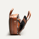 Sac à main homme en cuir cognac et toile grise équipé d'un espace pour ranger une tenue de bureau.