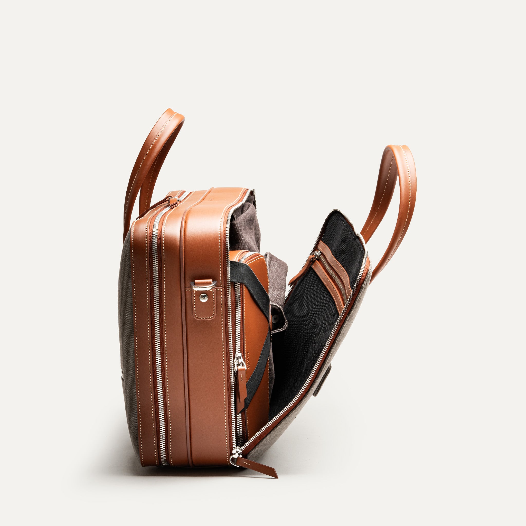 Sac à main homme en cuir cognac et toile grise équipé d'un espace pour ranger une tenue de bureau.