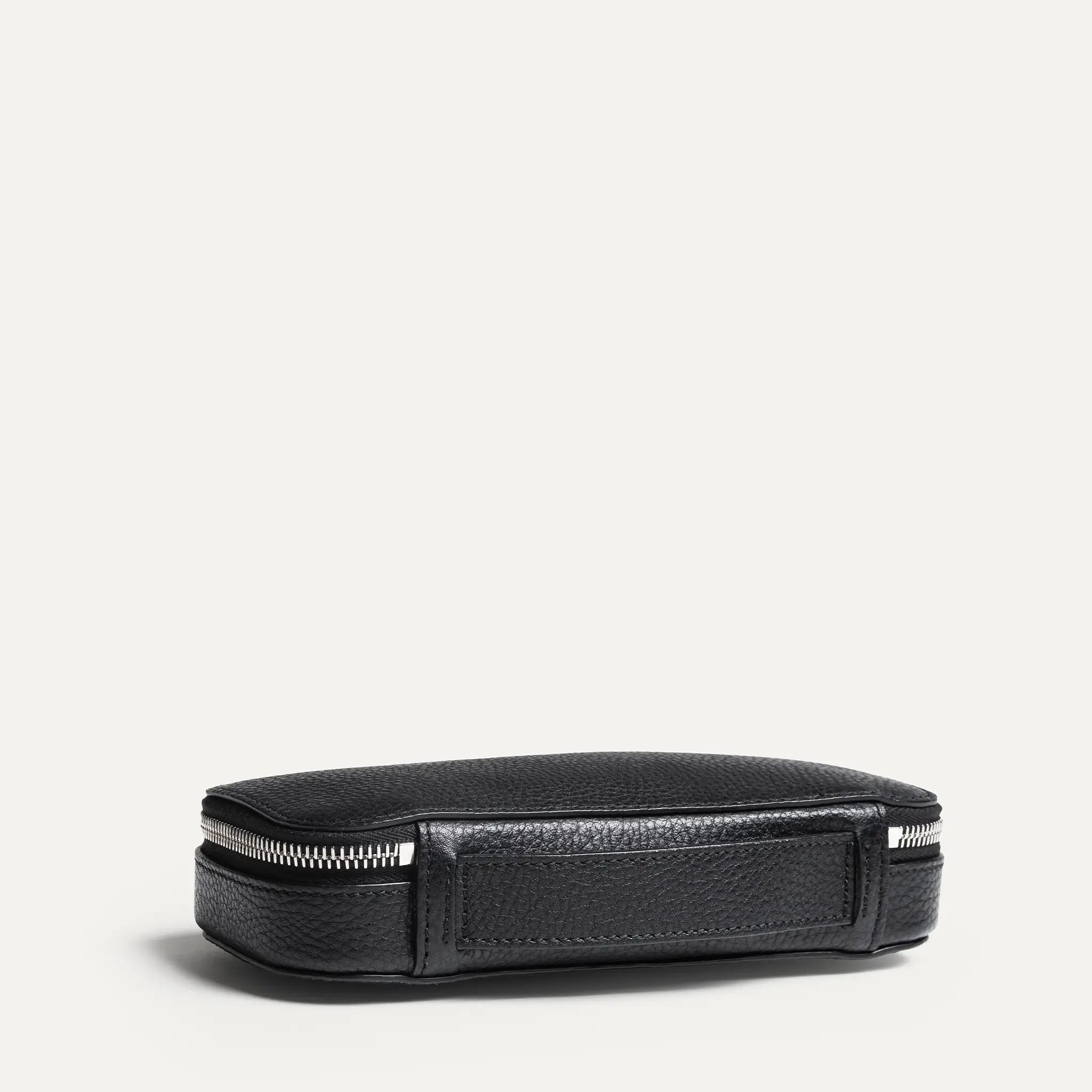 Vue de dos d'une trousse de toilette avec sa sangle pour la porter ou la suspendre, en cuir grainé noir et intérieur en Alcantara