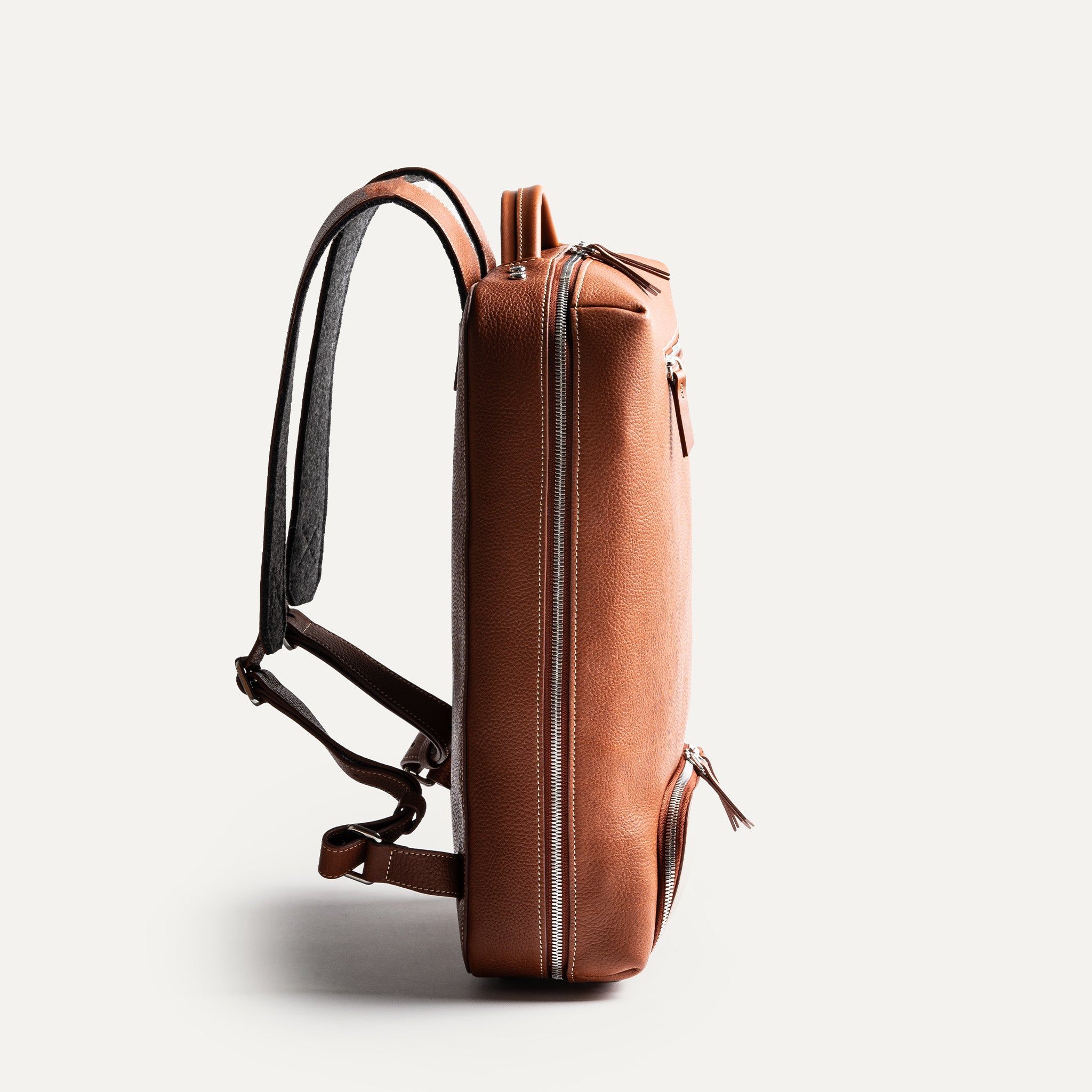 Sac à dos ordinateur fin en cuir cognac, design épuré et professionnel.