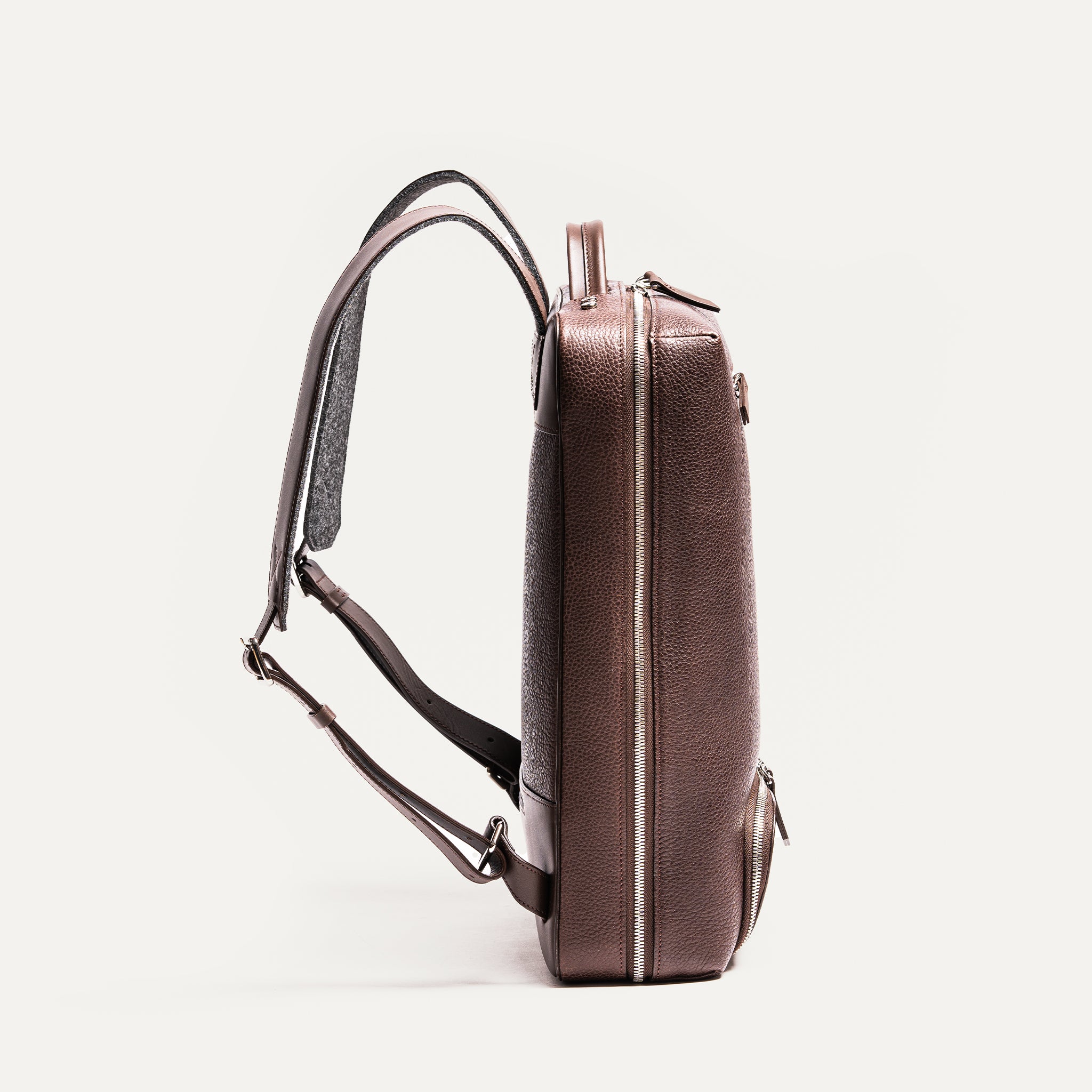 Profil mince et élégant d’un sac à dos cuir homme marron foncé, design moderne.