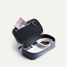 Trousse de toilette de voyage ouverte contenant passeport, chargeur et câbles rangés.