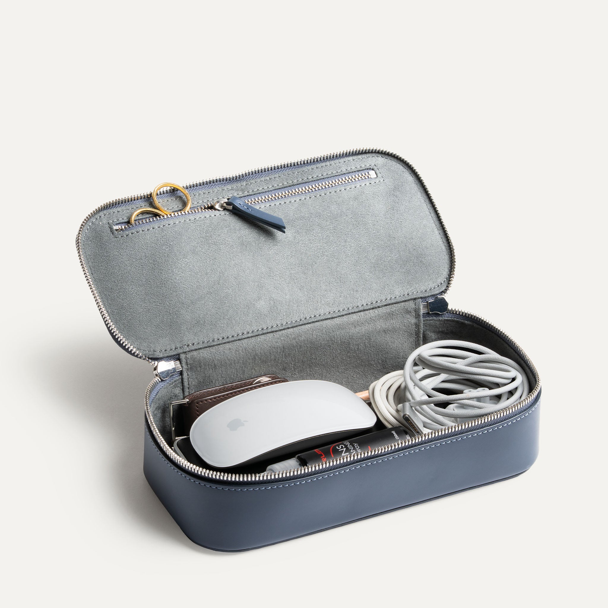 Trousse de toilette de voyage ouverte contenant passeport, chargeur et câbles rangés.