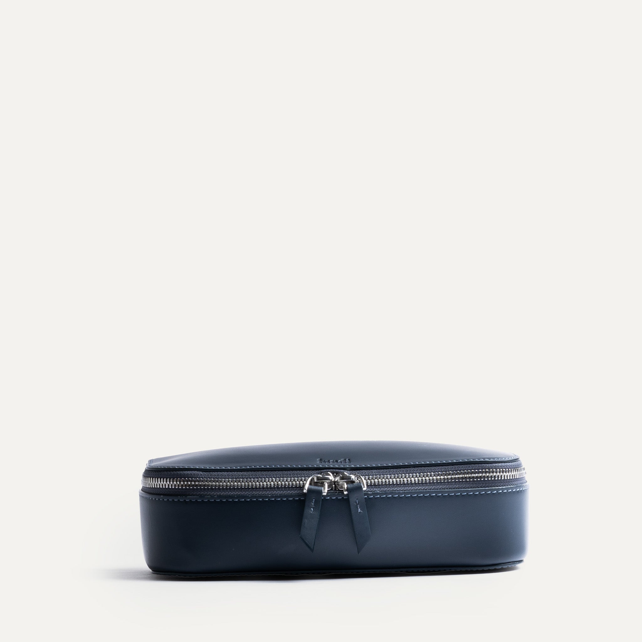 Trousse de toilette avion fermée, vue de face avec double zip et cuir bleu lisse.