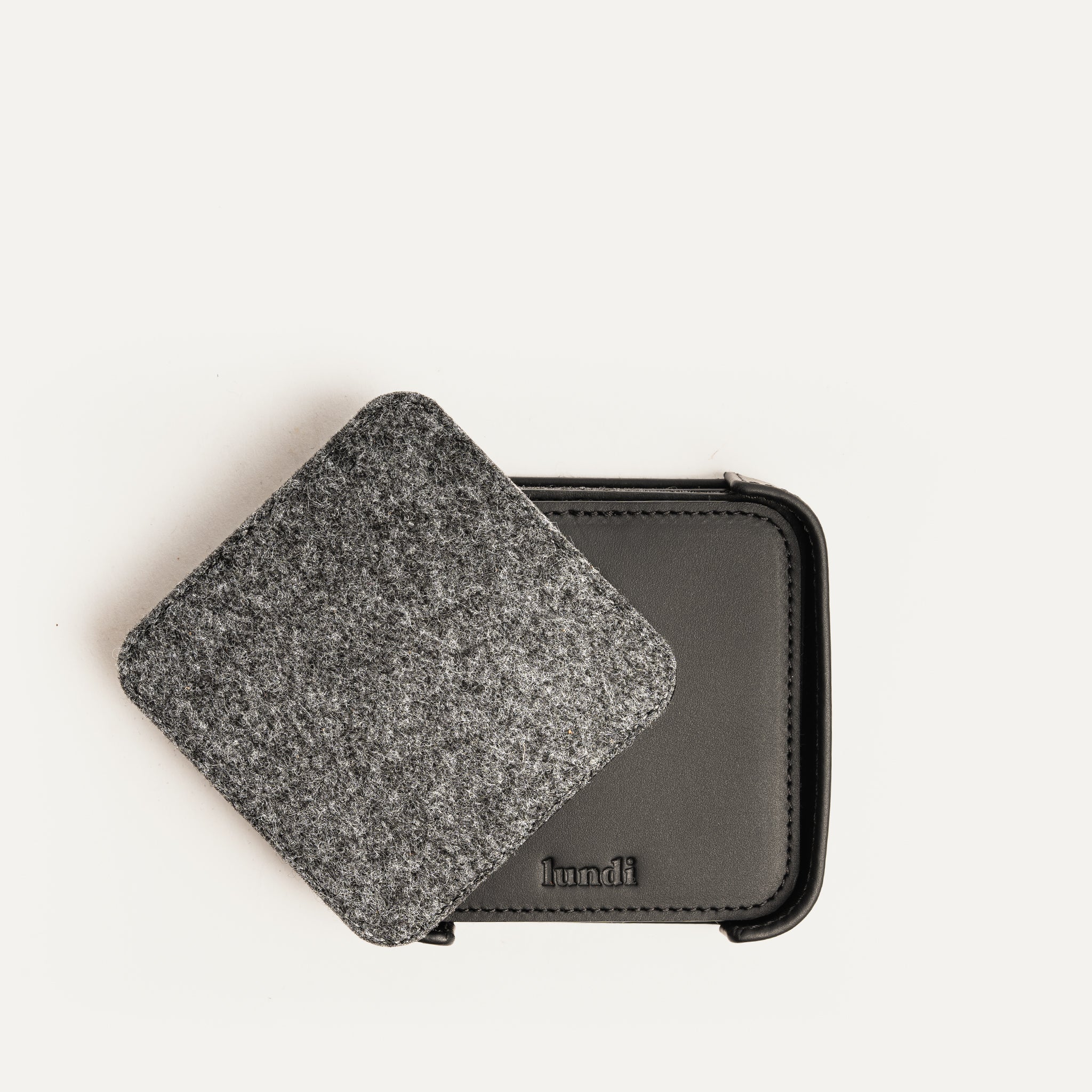 Dessous de verre personnalisé en cuir noir et feutre gris, superposés en présentation produit.