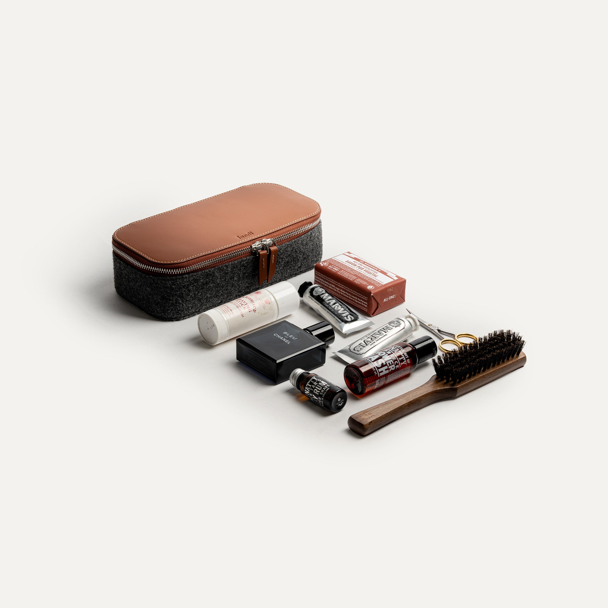 Trousse de toilette cuir pour homme posée à côté de produits de soin et accessoires de beauté, illustrant sa capacité de rangement