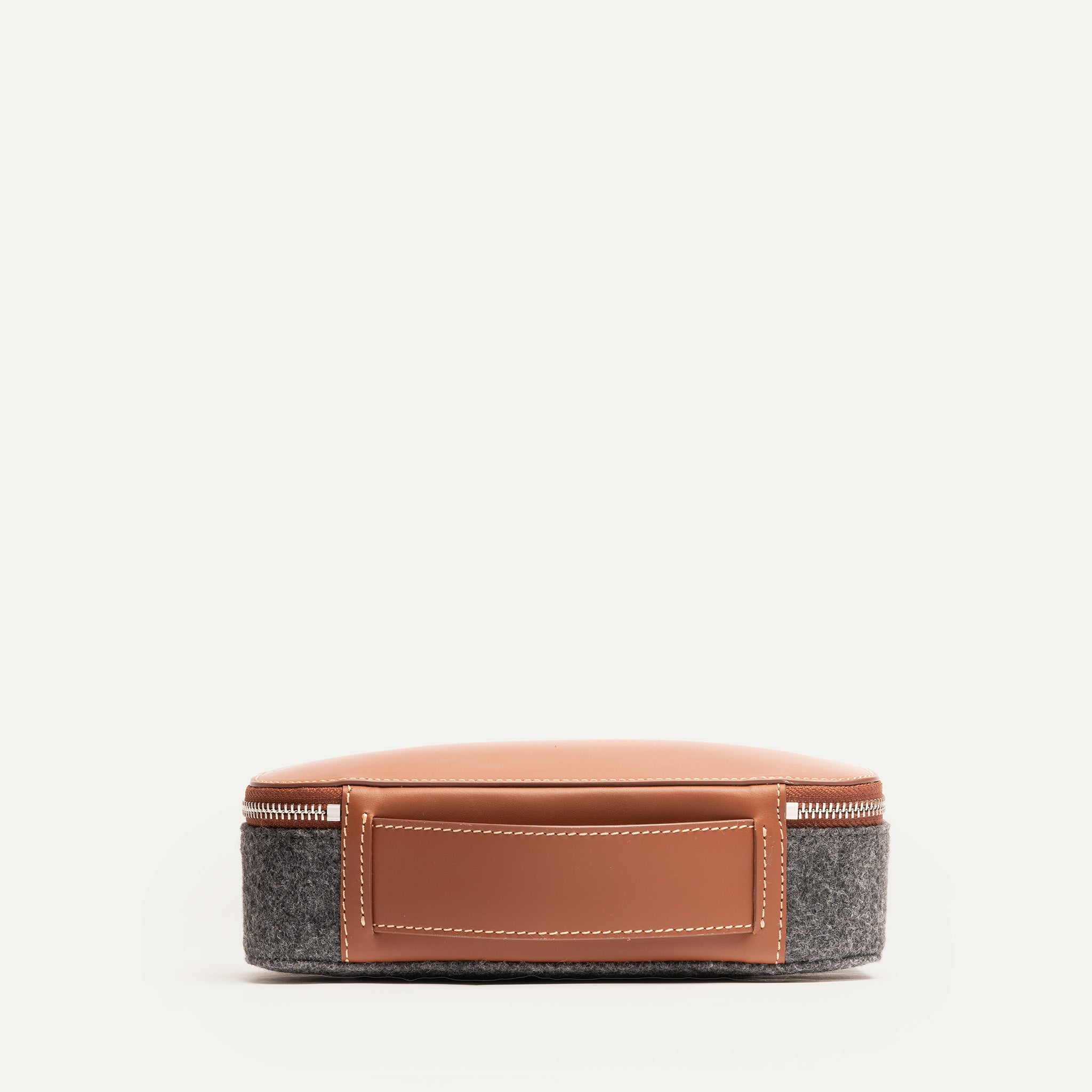 Trousse de toilette homme vue arrière, en feutre gris et cuir camel, avec poignée intégrée et couture soignée.