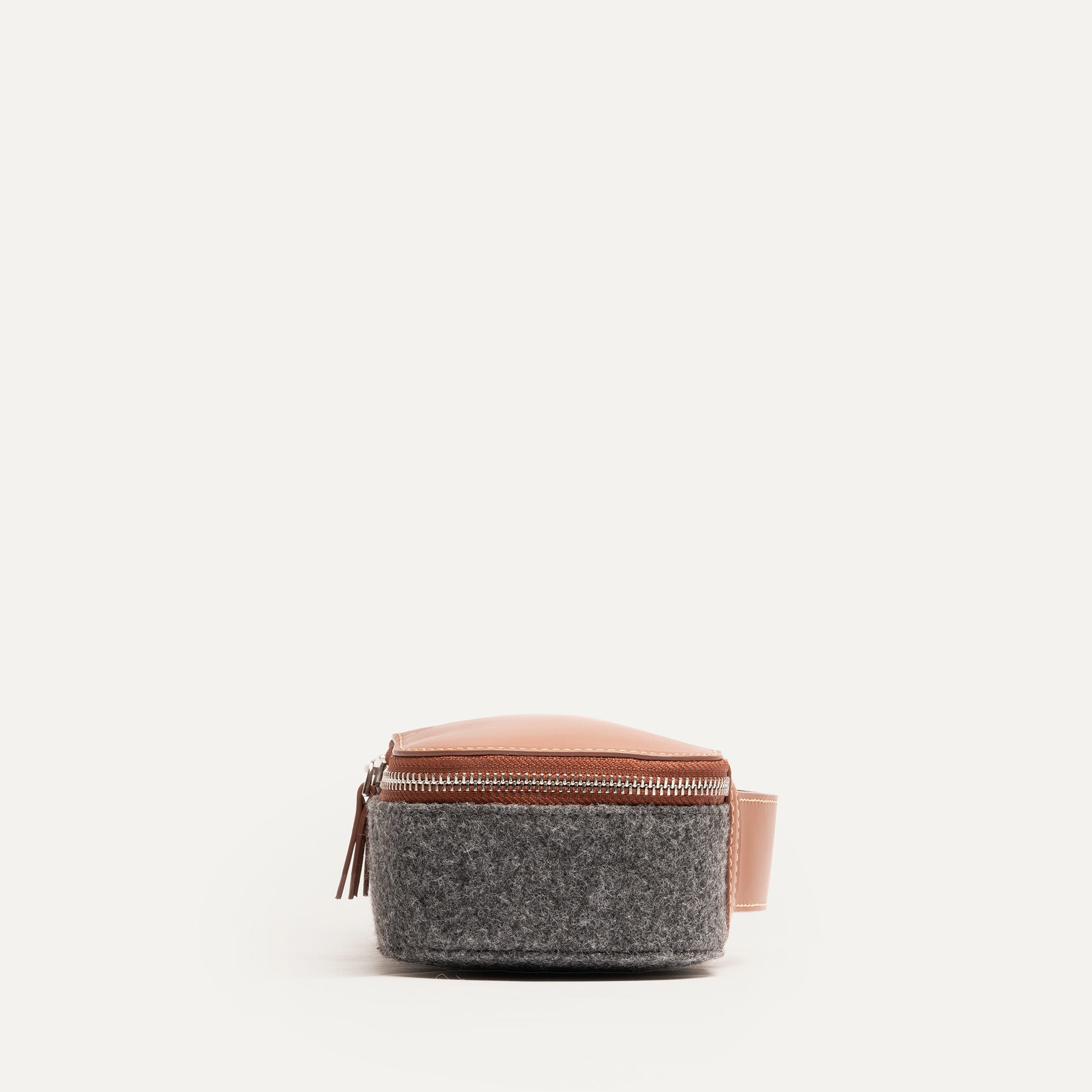 Trousse de toilette homme luxe vue de côté, en feutre gris et cuir camel, mettant en avant la qualité des matériaux.
