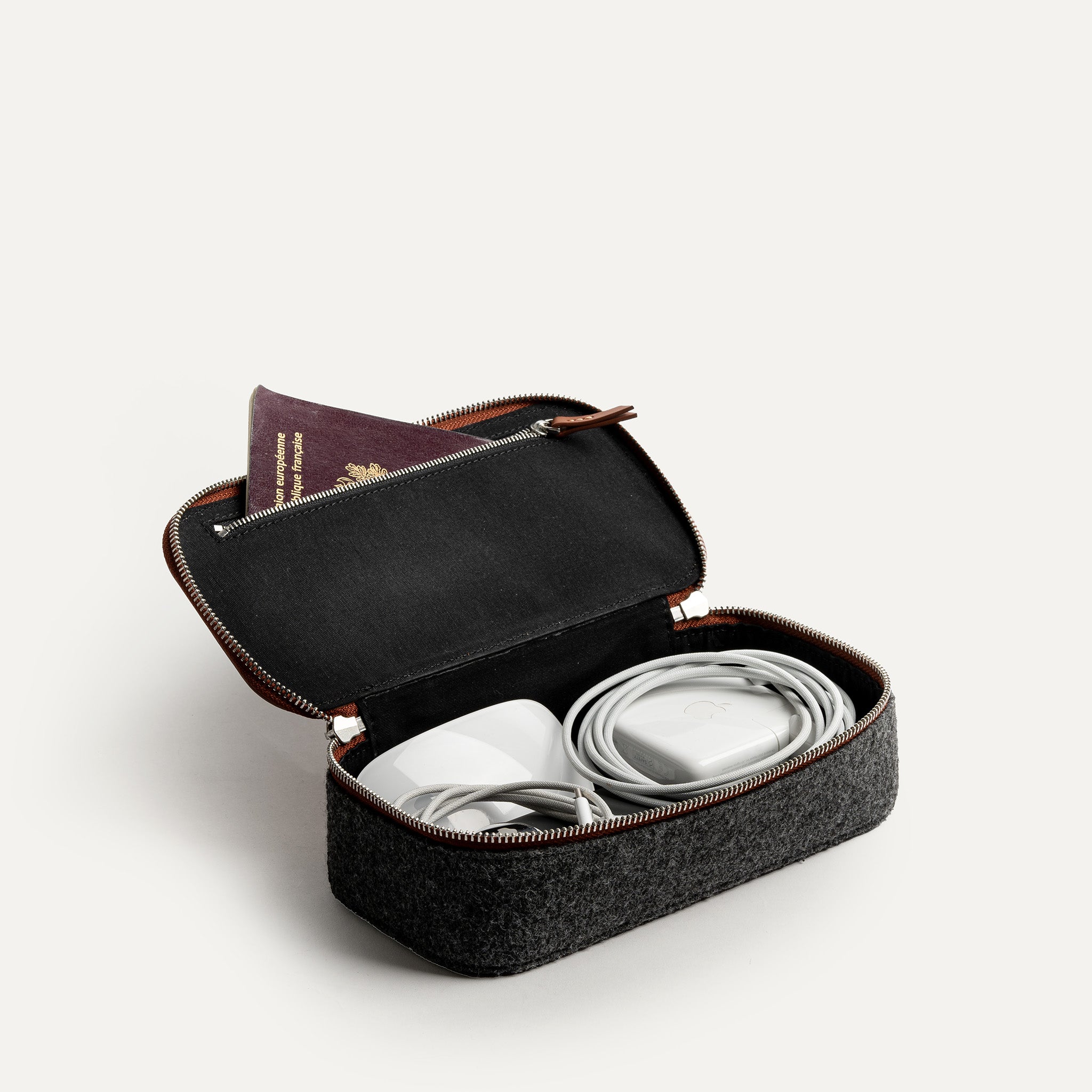 Trousse de toilette de voyage ouverte utilisée comme rangement pour câbles et passeport, illustrant sa polyvalence.