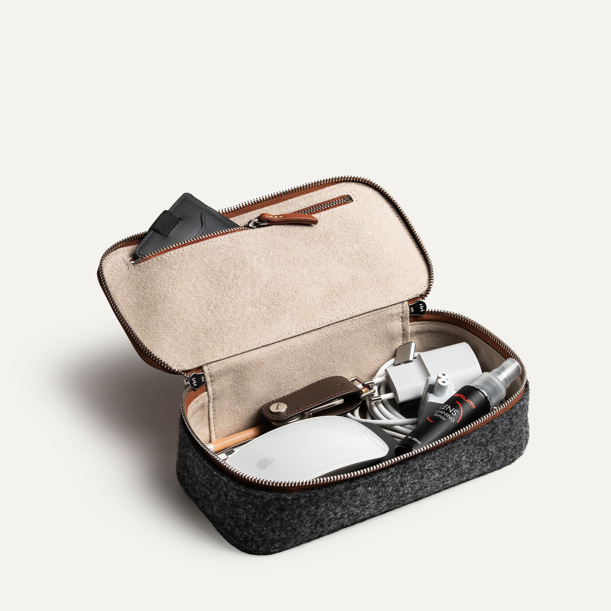 Trousse de toilette de voyage ouverte utilisée comme rangement pour câbles et passeport, illustrant sa polyvalence.