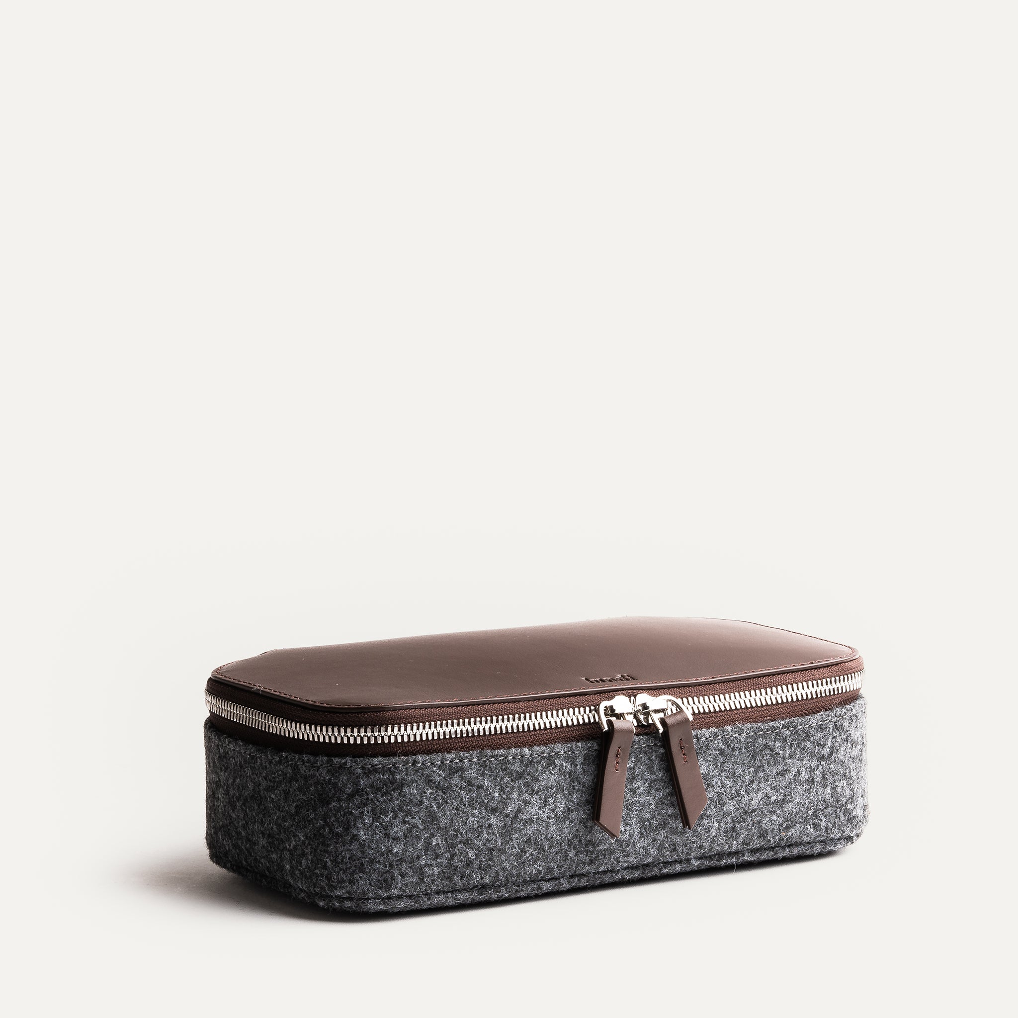 Trousse de toilette homme cuir en feutre gris et cuir marron, fermée avec fermeture éclair argentée.