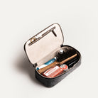 Trousse de toilette pour avion ouverte, montrant des produits essentiels et accessoires de soin.