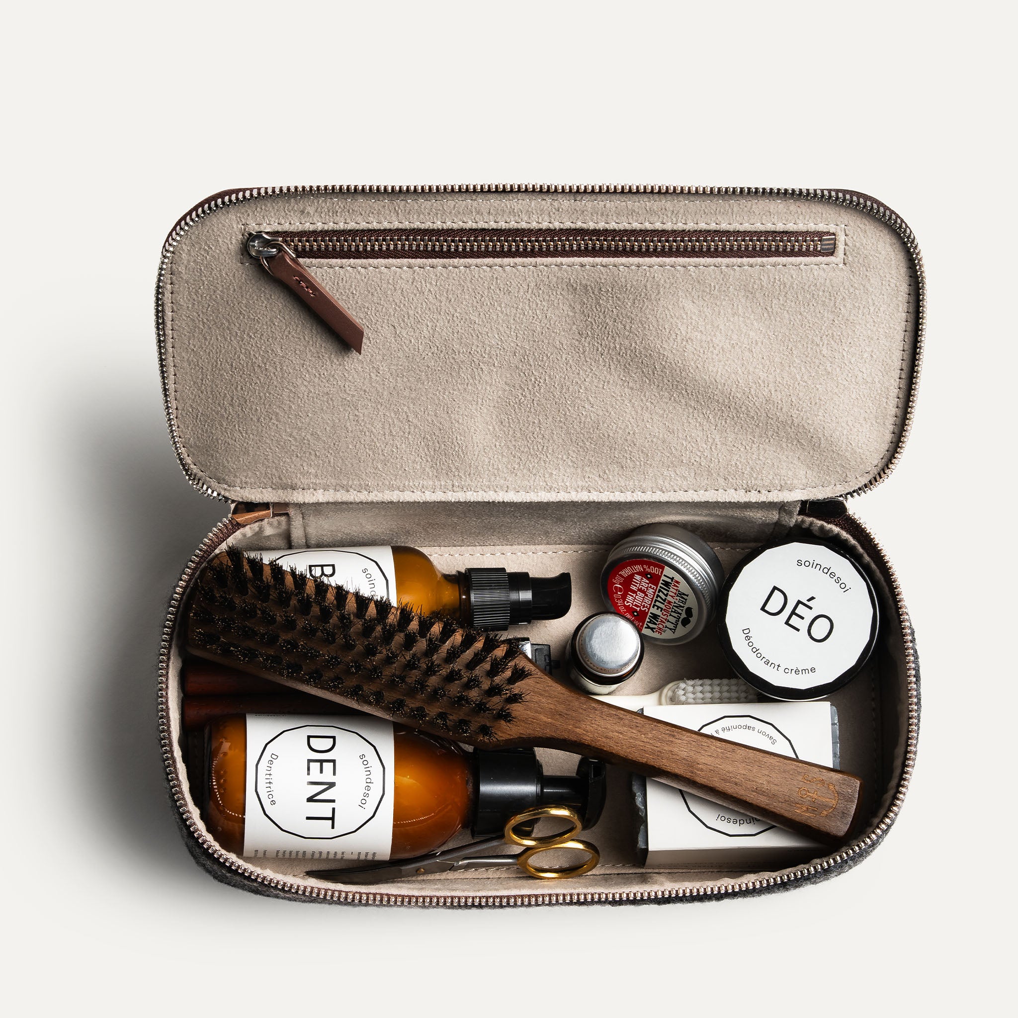 Trousse de toilette pour avion ouverte, montrant des produits essentiels et accessoires de soin.
