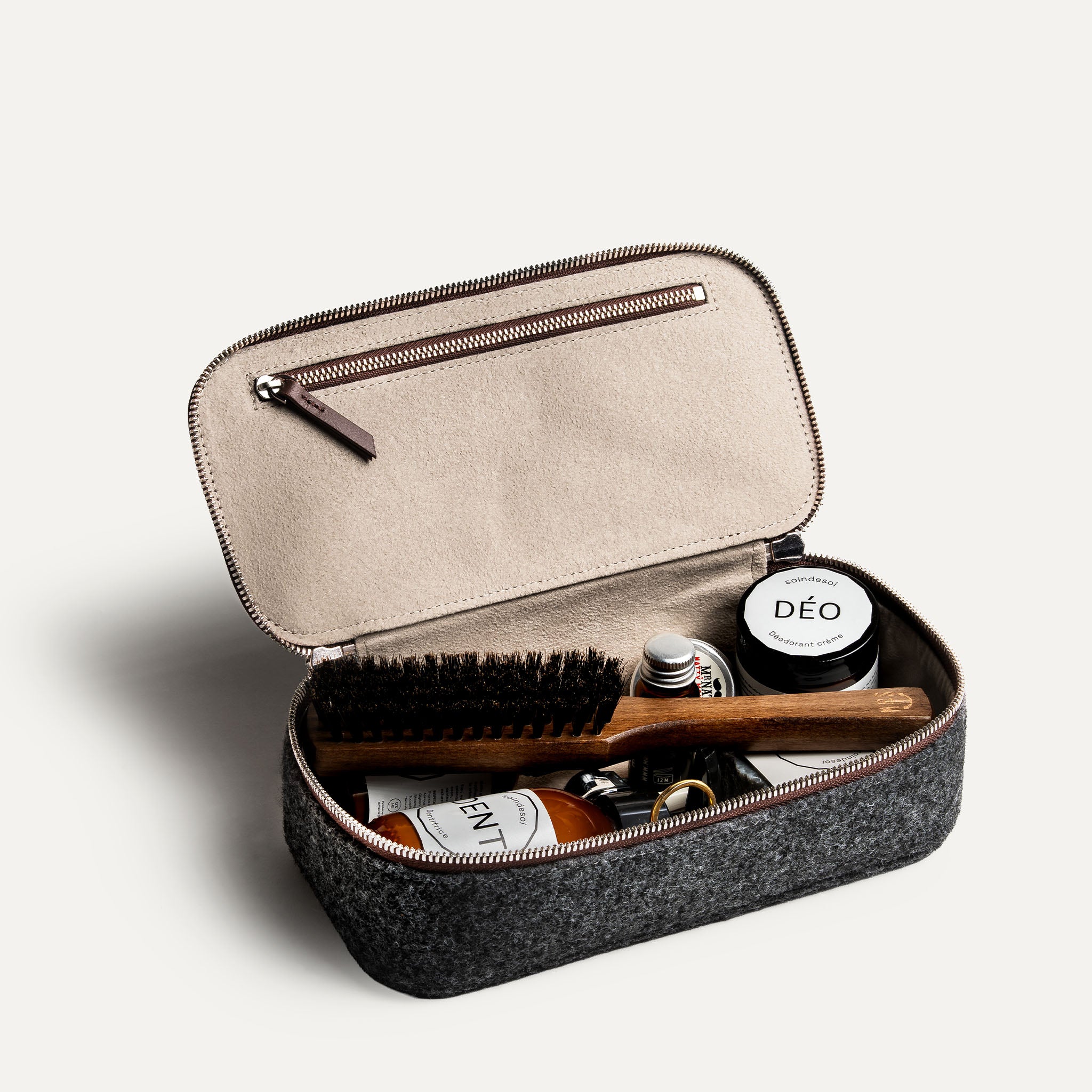 Trousse de toilette cuir pour homme vue ouverte, contenant des produits de soin et accessoires.