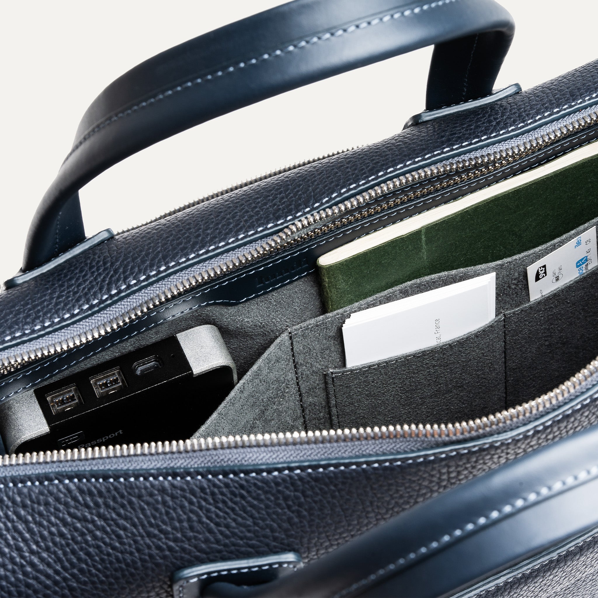 Compartiment principal d’un sac homme travail bien agencé avec poches pour disque dur, carnet et cartes.