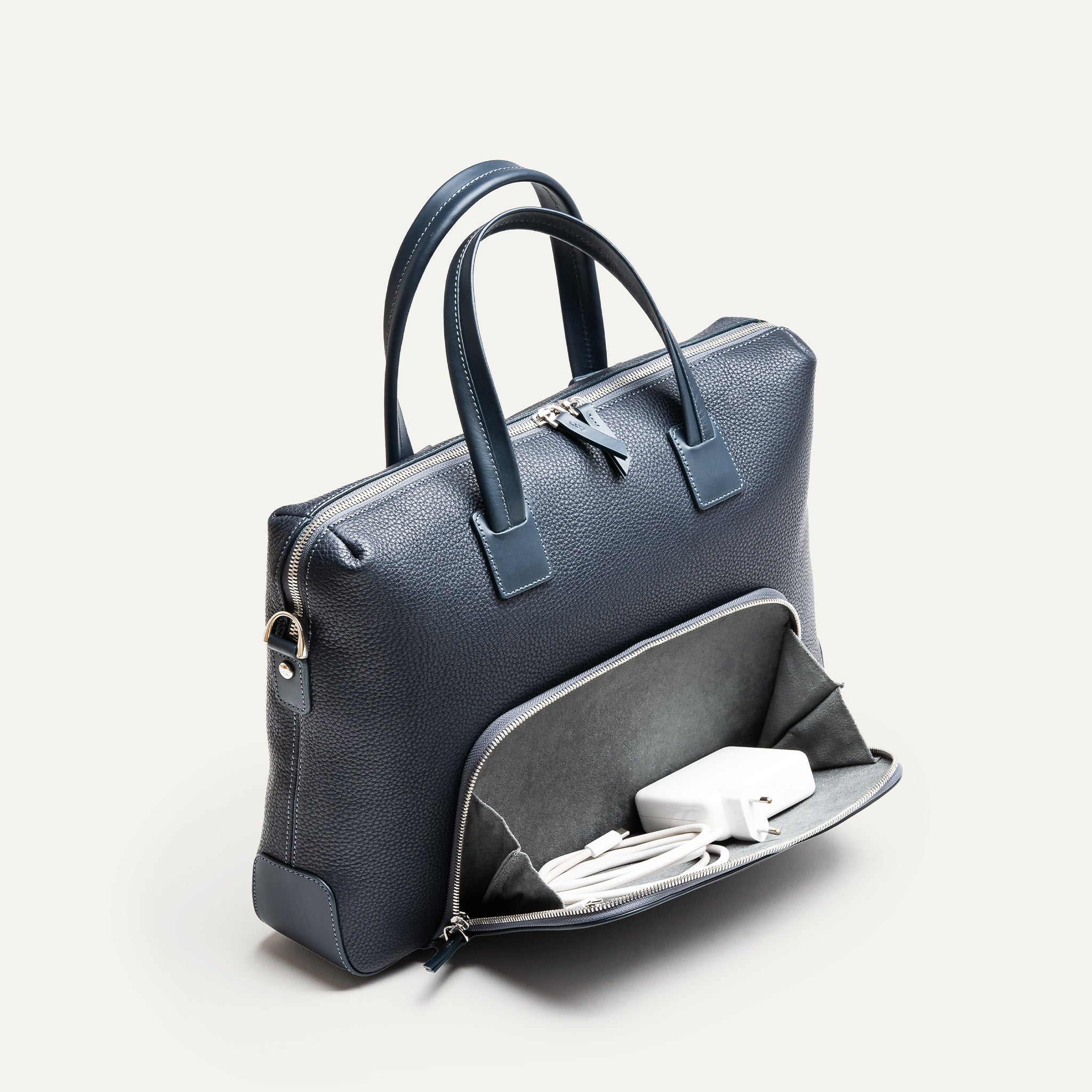 Compartiment avant d’un porte document homme en cuir grainé bleu, ouvert avec un chargeur.