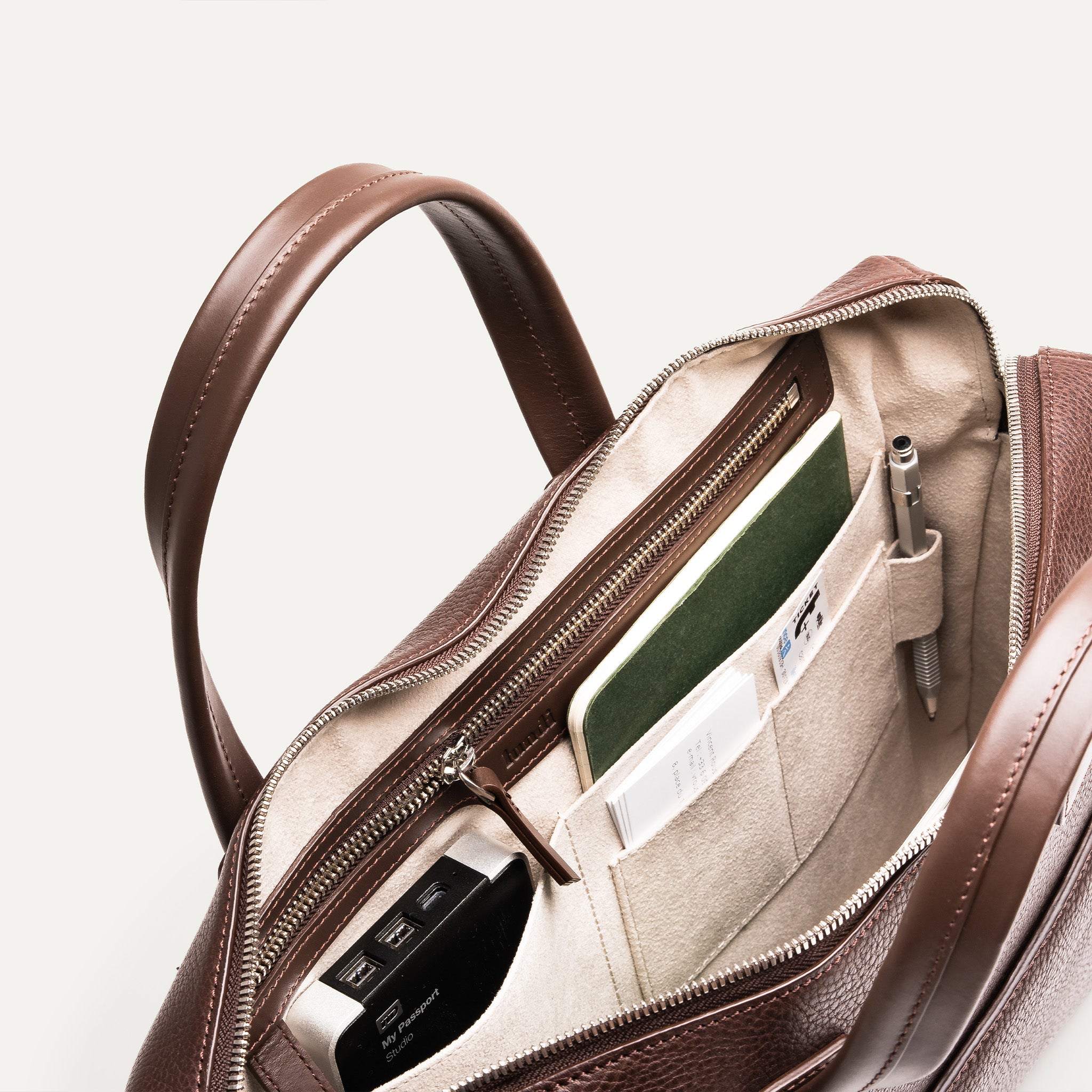 Sac à main homme en cuir marron, compartimenté pour ranger des objets essentiels du quotidien.