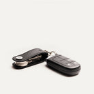 Porte clé en cuir avec clé de voiture attachée, posé incliné montrant une vue latérale du produit.