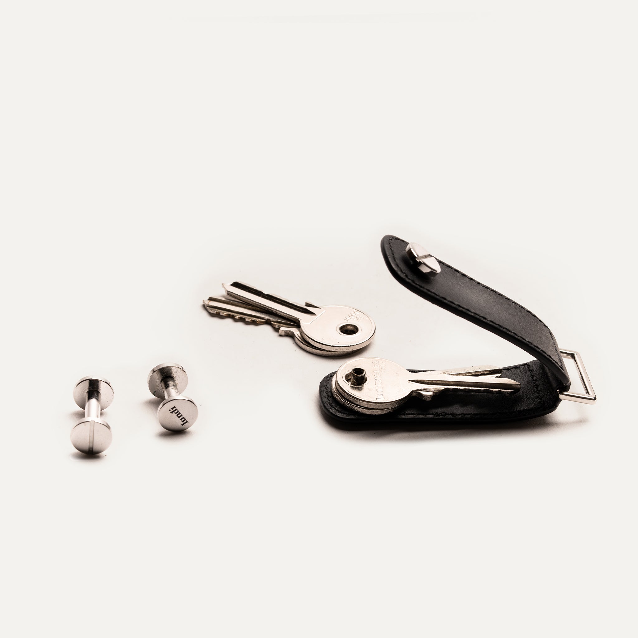 Porte clé à personnaliser en cuir ouvert avec clés et vis démontées posées à côté.