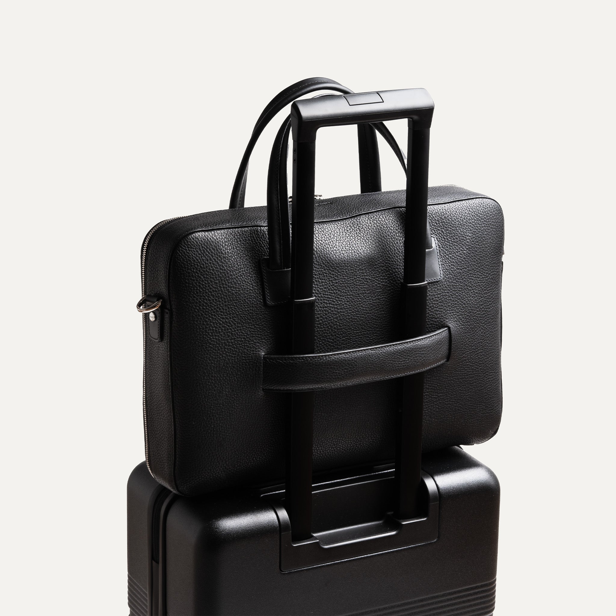 Sac à bandoulière homme fixé à une valise trolley.