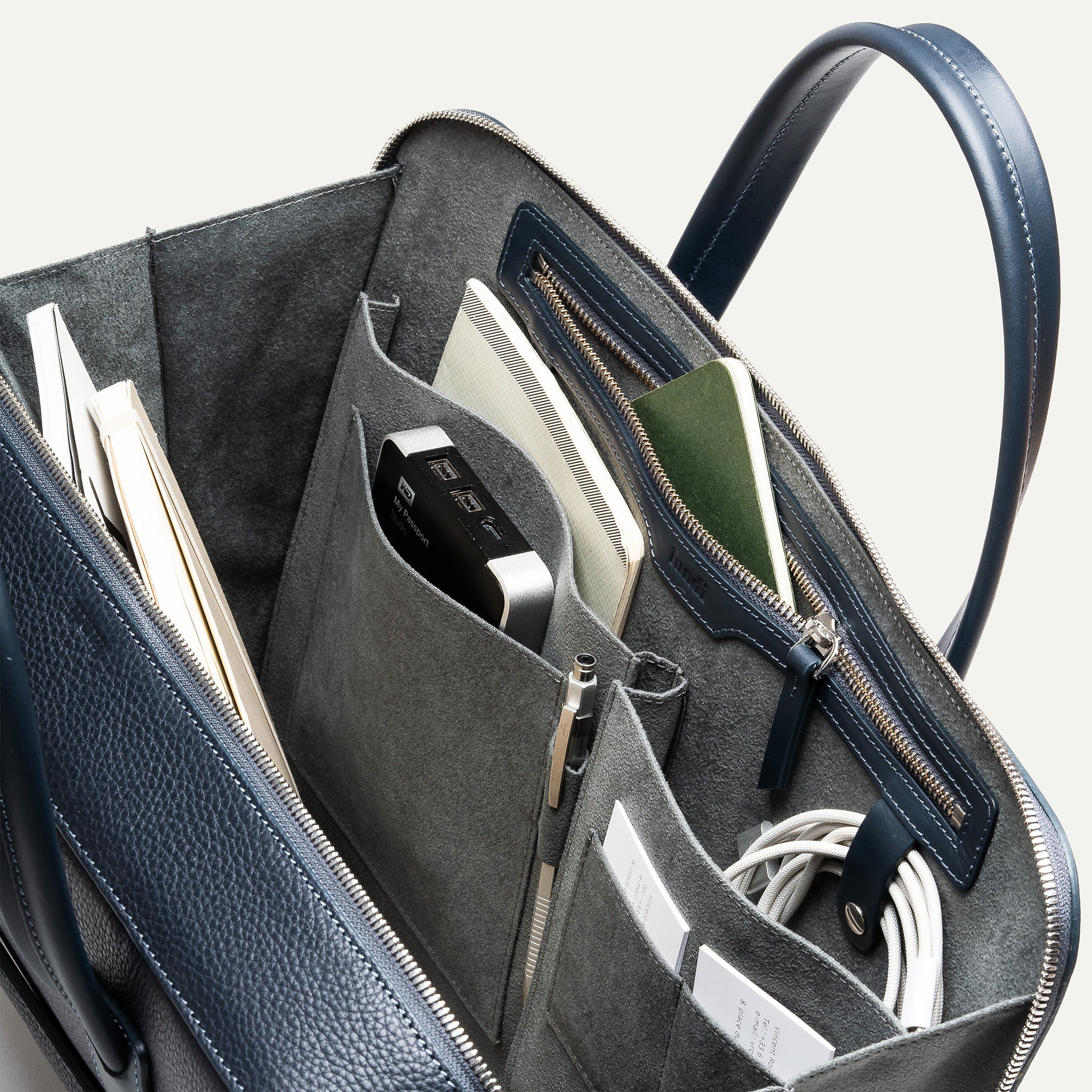 Organisation interne d’un briefcase en cuir marine avec bandoulière amovible.