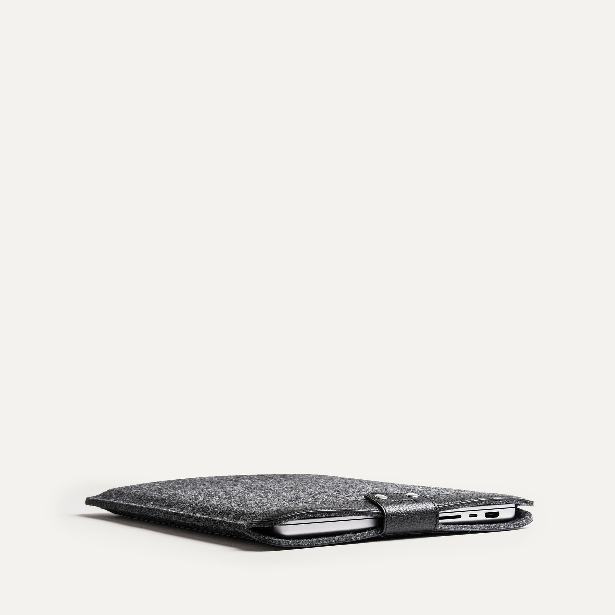 Slim laptop sleeve with MacBook, leather and felt materials, perfect for daily use.