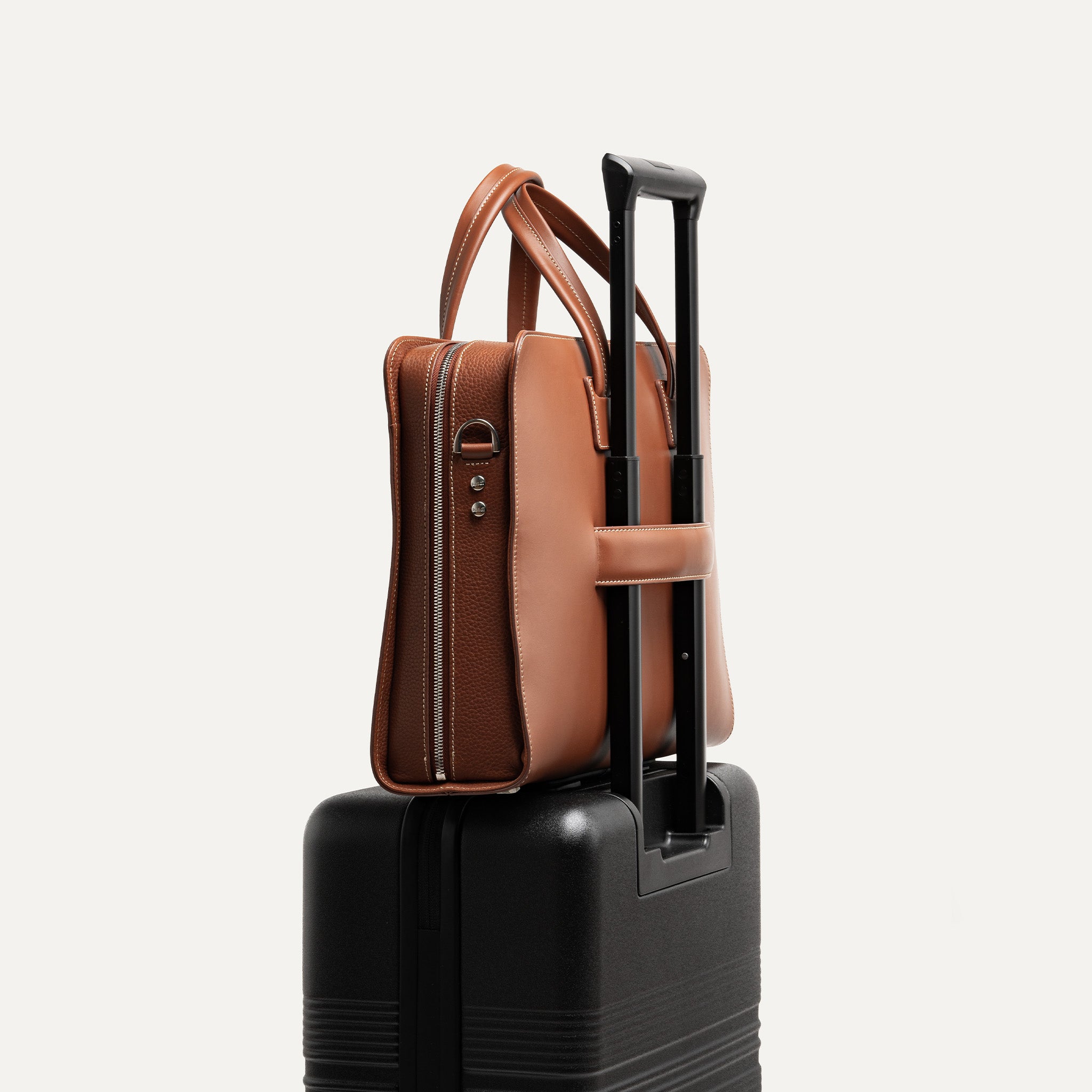 Sac homme travail en cuir naturel avec poche dédiée pour câbles et prise intégrée et équipé d'un passant trolley pour être porté sur une valise.