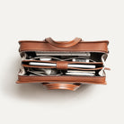 Sac à main homme en cuir raffiné avec multiples rangements pour smartphone, ordinateur, carnet et accessoires.