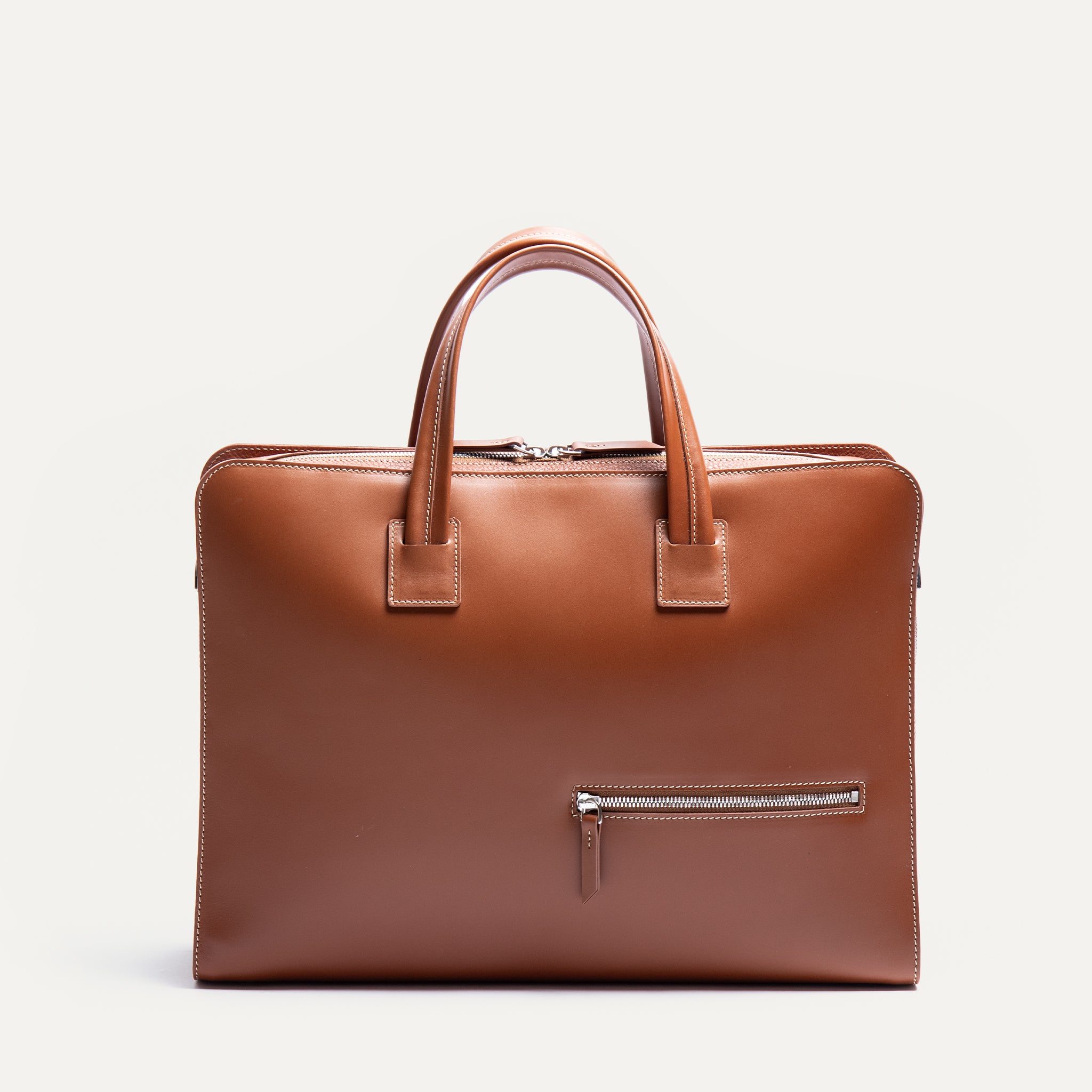 Briefcase en cuir de couleur cognac équipé d'une bandoulière et de rangements fonctionnels.