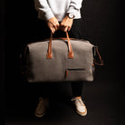 Men’s leather travel bag resting atop a rolling suitcase, with its trolley sleeve visible for easy cabin use.