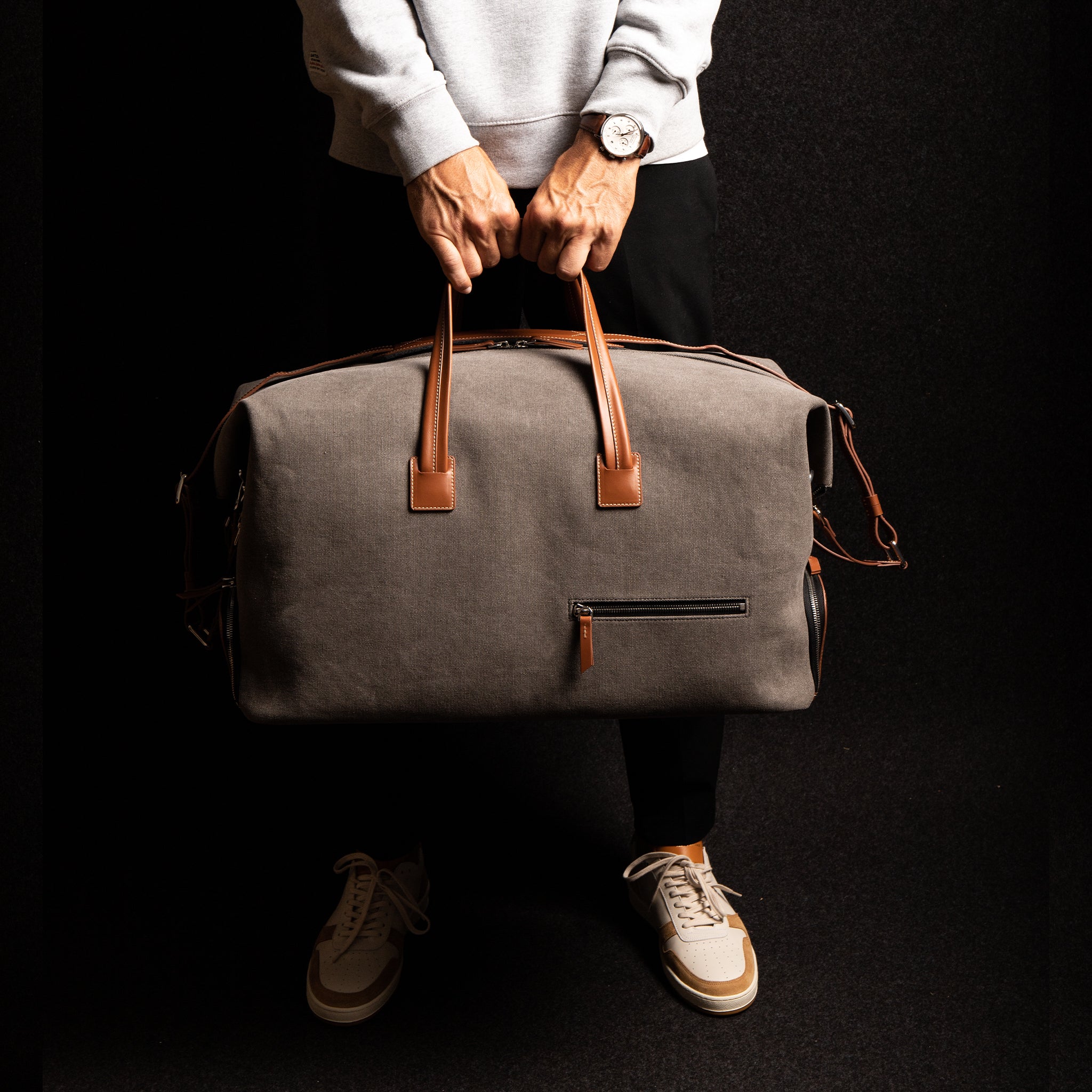 Men’s leather travel bag resting atop a rolling suitcase, with its trolley sleeve visible for easy cabin use.