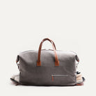 Men’s leather travel bag featuring a detachable shoulder strap and side zip pocket for shoes, suspended.