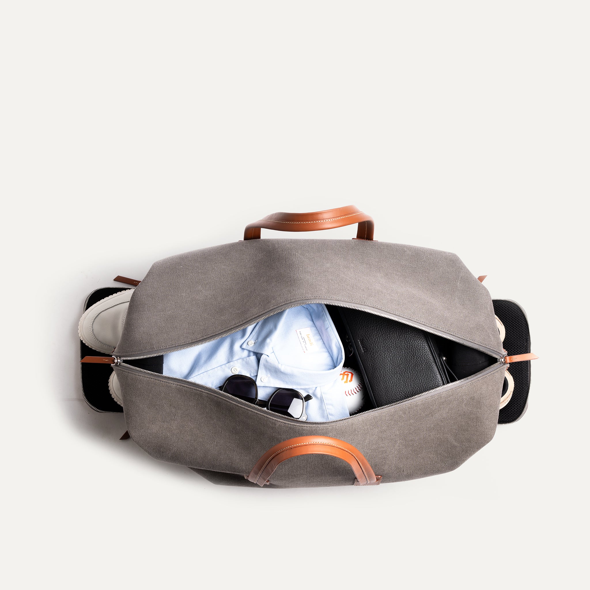 Men’s leather travel bag open from above, revealing organized Alcantara-lined interior with laptop sleeve, shoes and accessories.