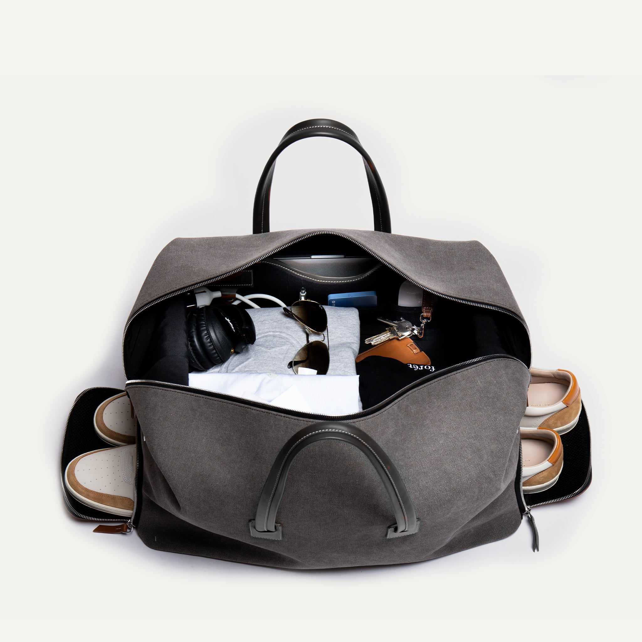 Sac en cuir de voyage pour femme luxueux en toile grise avec ses multiples compartiments, il offre une organisation optimale pour tous vos essentiels.