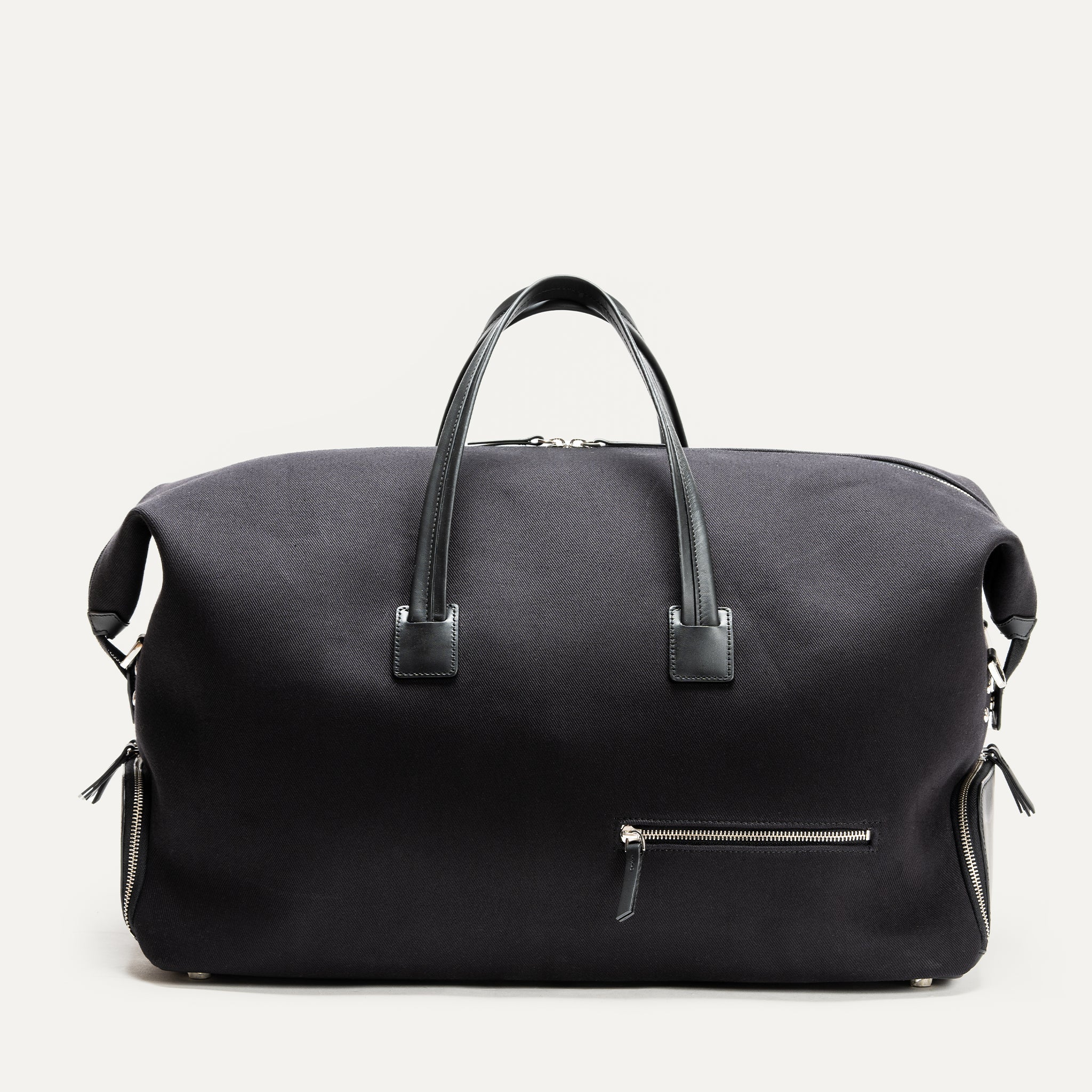 Vue frontale d’un sac week end homme en tissu noir avec anses cuir et poche extérieure zippée, conçu pour les voyages cabine.