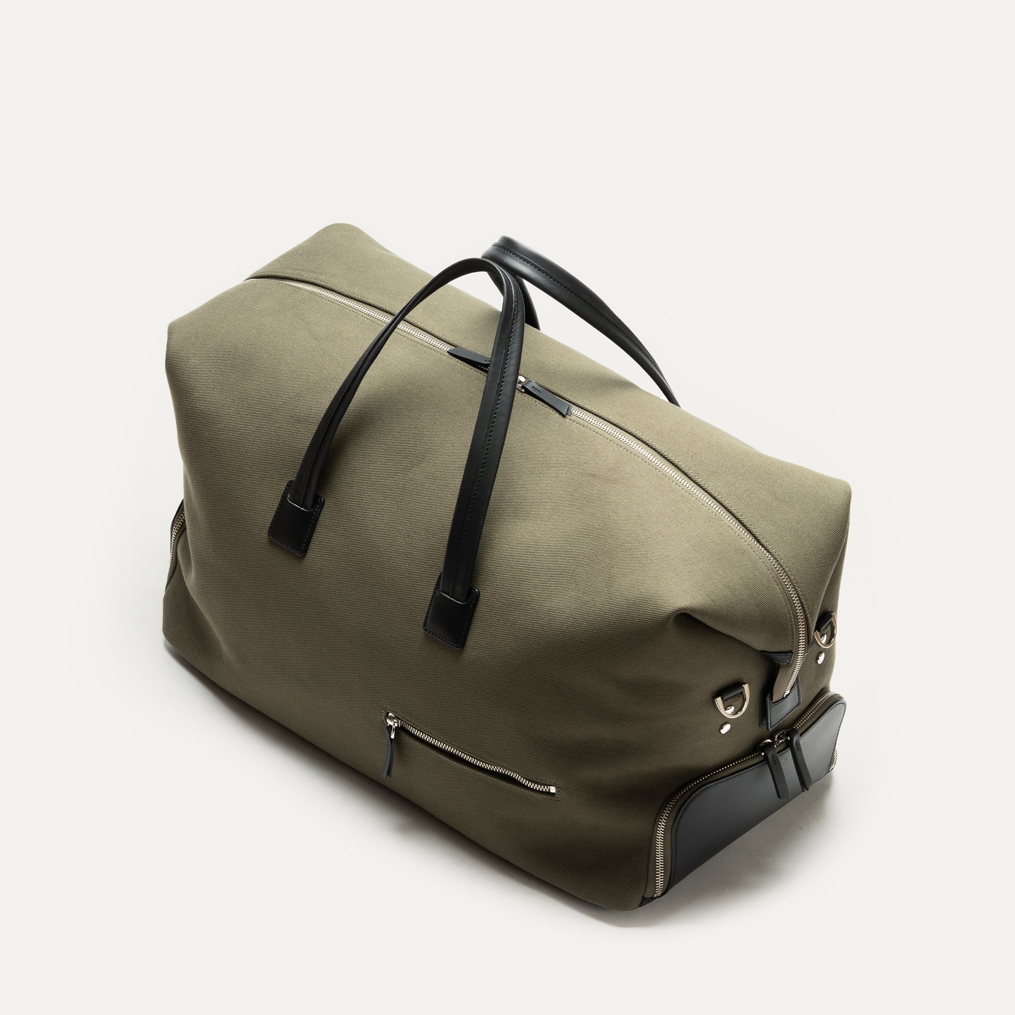 Sac weekender élégant avec poches extérieures zippées, confectionné en toile kaki et cuir noir.