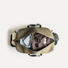 Vue intérieure d’un sac de voyage cabine kaki avec vêtements et accessoires soigneusement rangés.