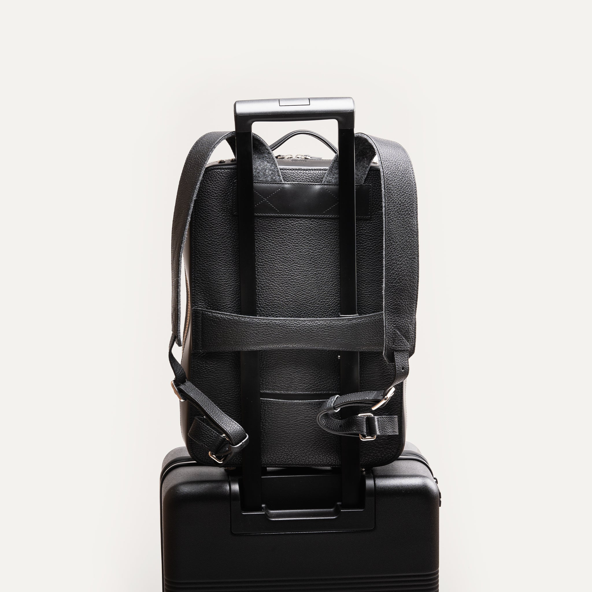 sac à dos en cuir gris et noir pour homme avec bretelles ajustables et passant trolley pour la valise.
