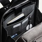 sac à dos homme en cuir et toile grise avec poches tech, stylos, carnet et rangement ordinateur.